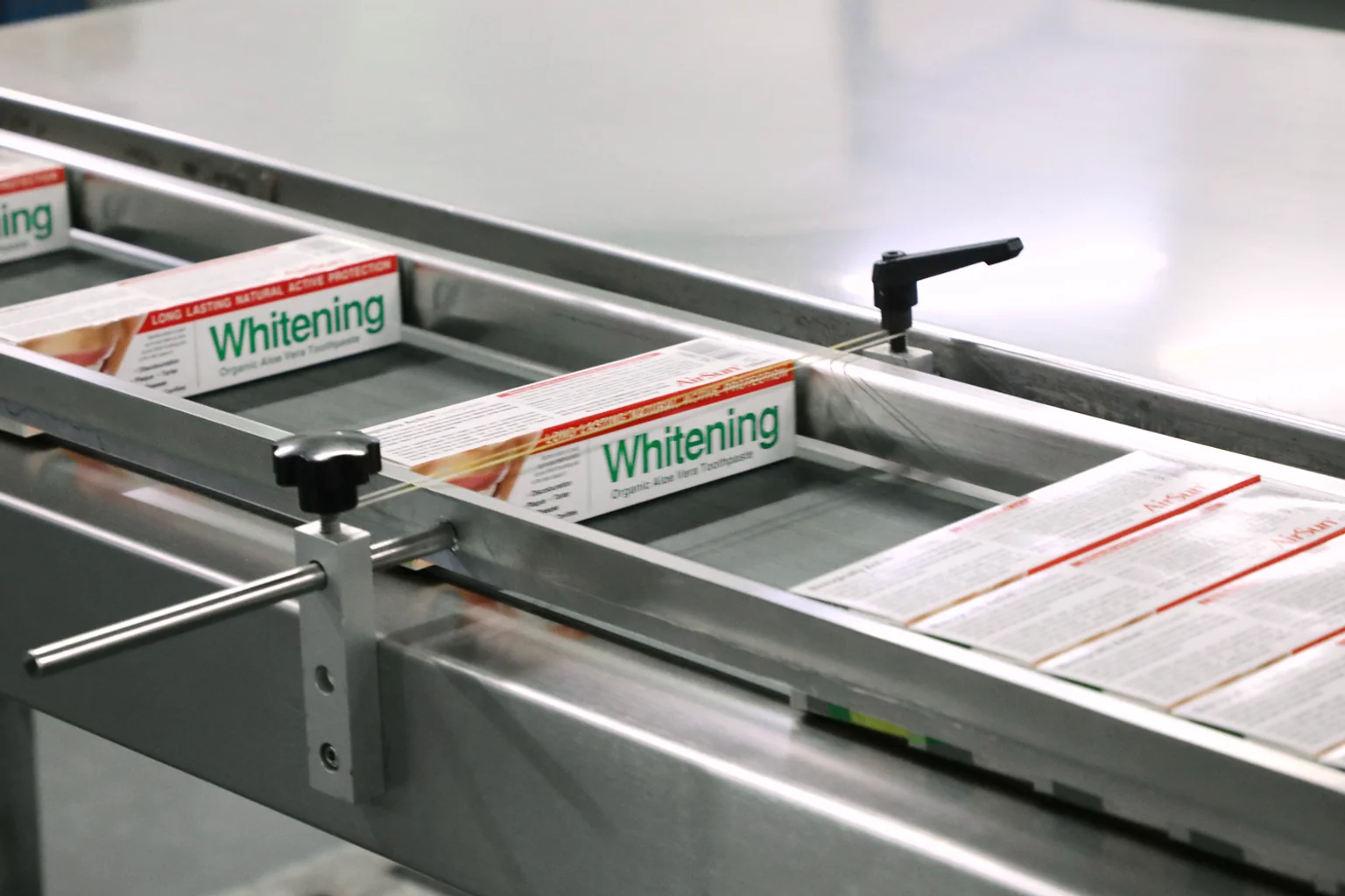 Packaged toothpaste cartons moving along a production conveyor.